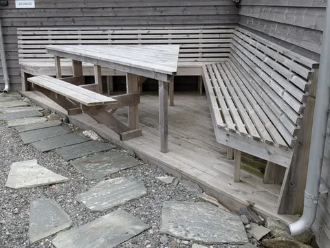The sheltered corner of the service building at Ryvarden, with a picnic table and long timber benches on a wooden deck