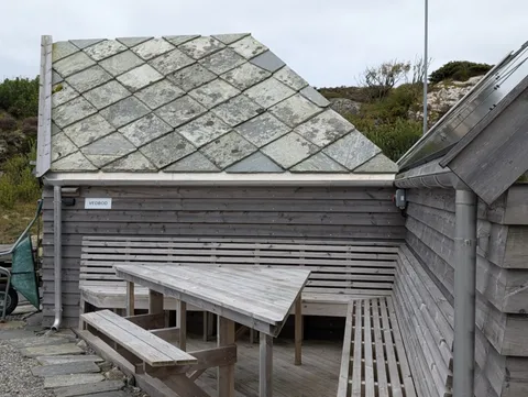 The service building at Ryvarden seen from outside, showing its diamond-patterned slate roof and grey timber cladding
