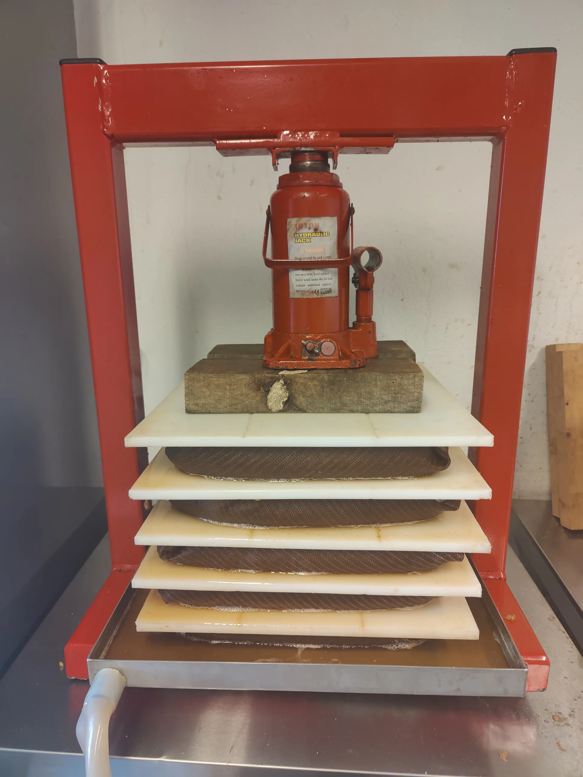 A hand-built apple press loaded with five cloth-wrapped layers of pomace