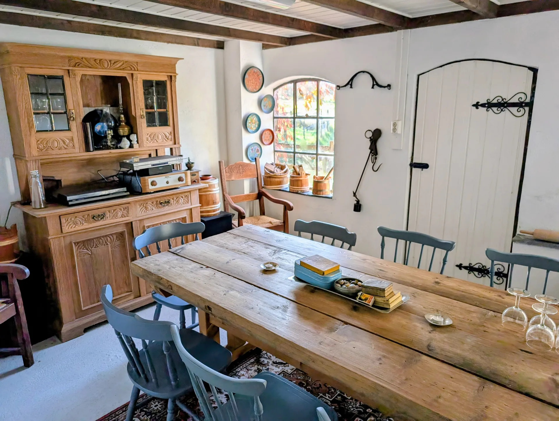 Old barn lunch room with a long plank table, blue chairs and a carved pine dresser
