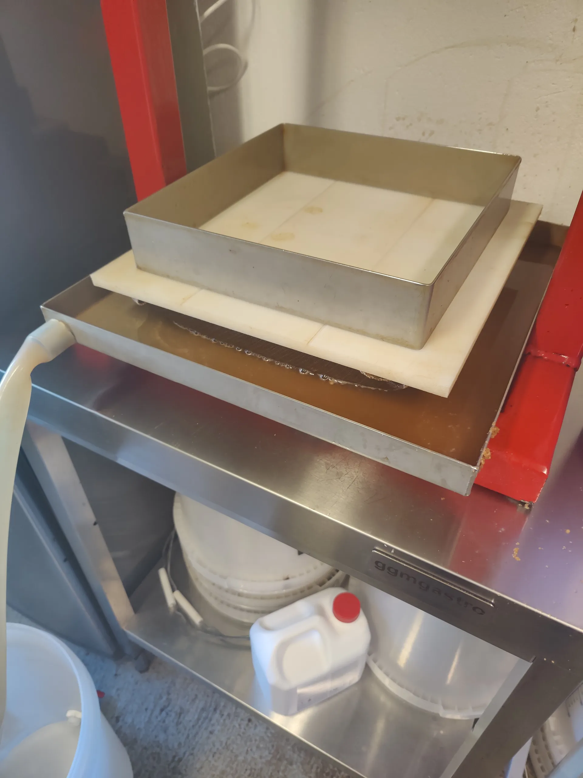 An empty stainless steel press frame sitting on the press plate, ready to fill