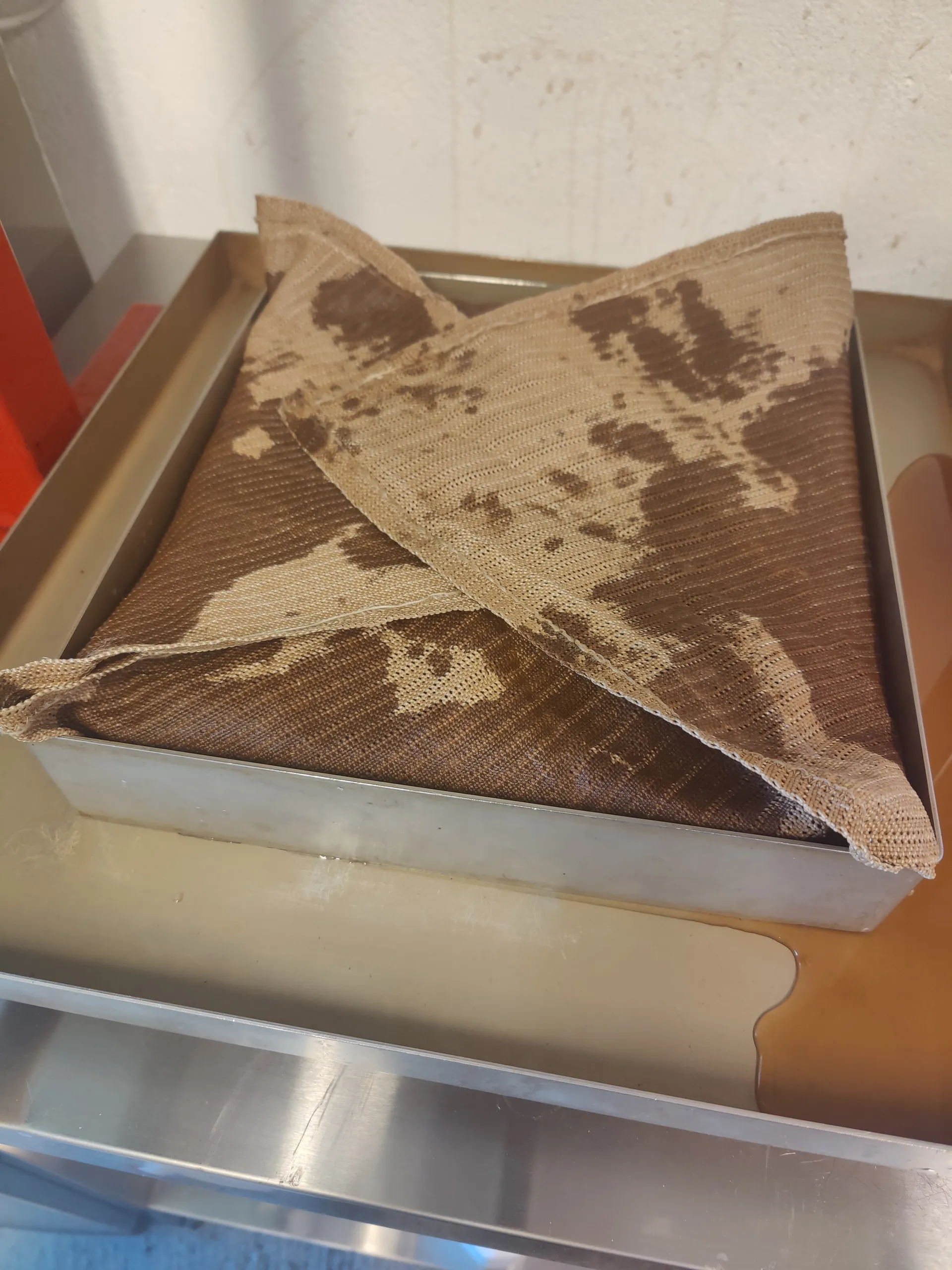 Apple pomace wrapped in press cloth inside a stainless steel frame